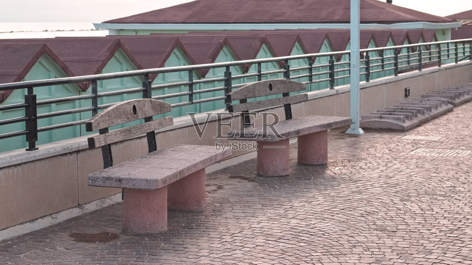 地中海海岸海滩小屋前人行道上的两张混凝土长椅(意大利，佩萨罗)照片摄影图片