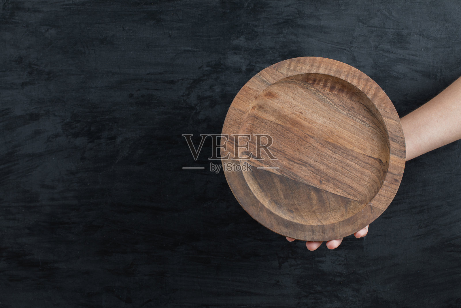 拿着一块圆形木板，背景是黑色照片摄影图片