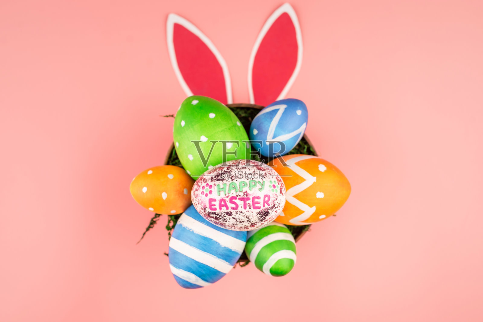明亮的复活节彩蛋，粉粉背景的纸兔子耳朵。俯视图照片摄影图片