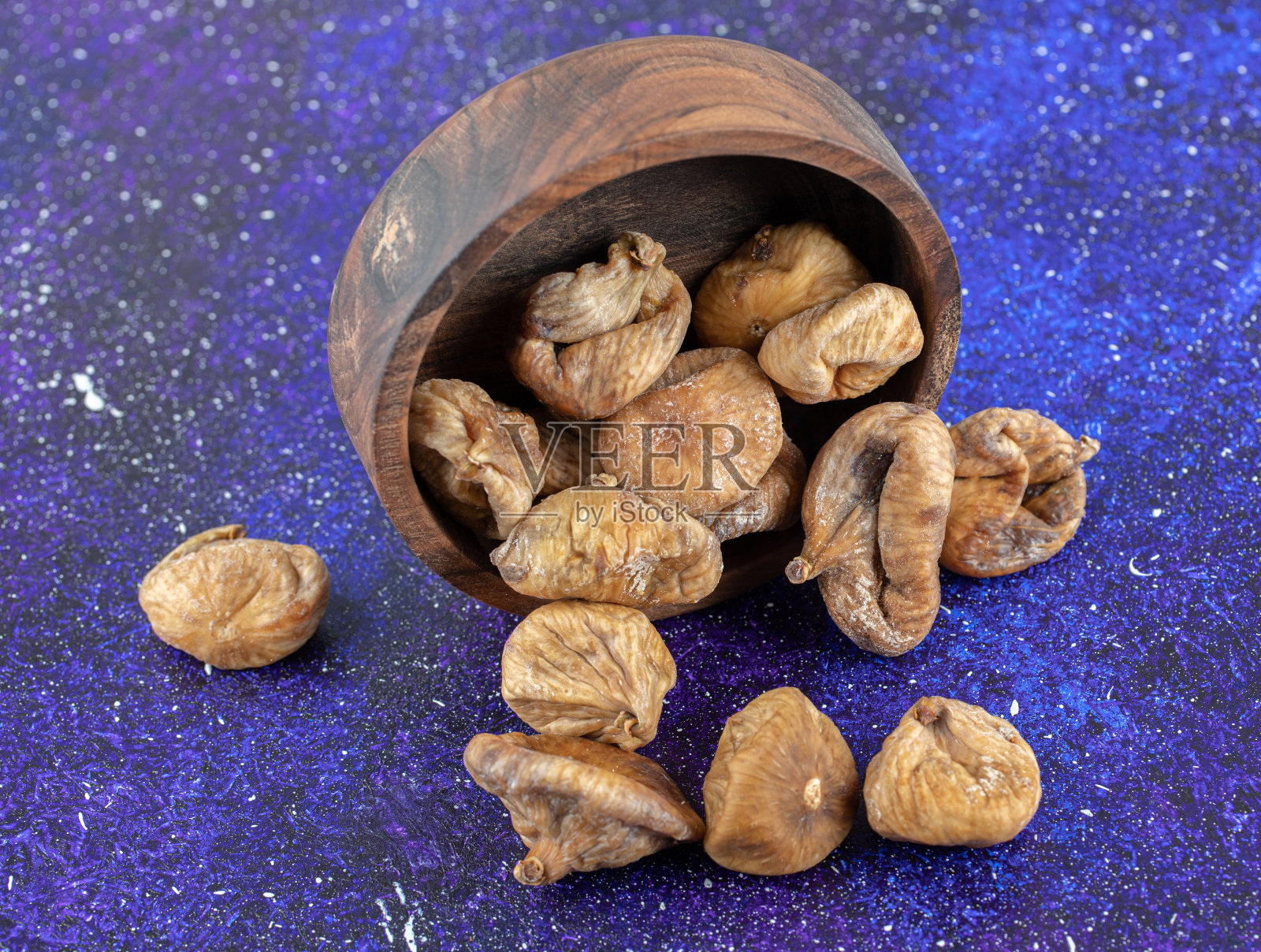 蓝色背景上的一碗干无花果照片摄影图片