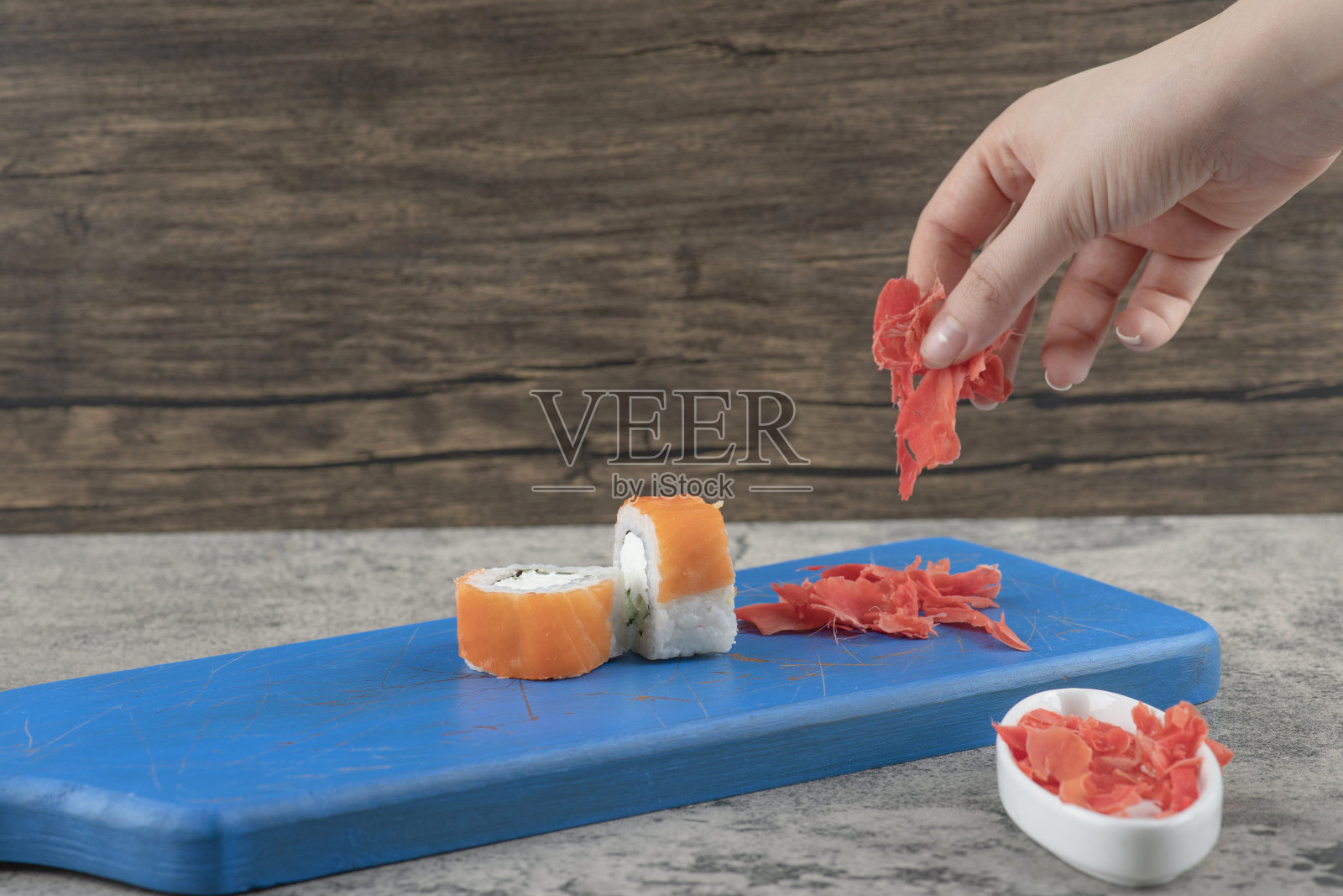 女性手从蓝色砧板上采摘腌制的姜照片摄影图片