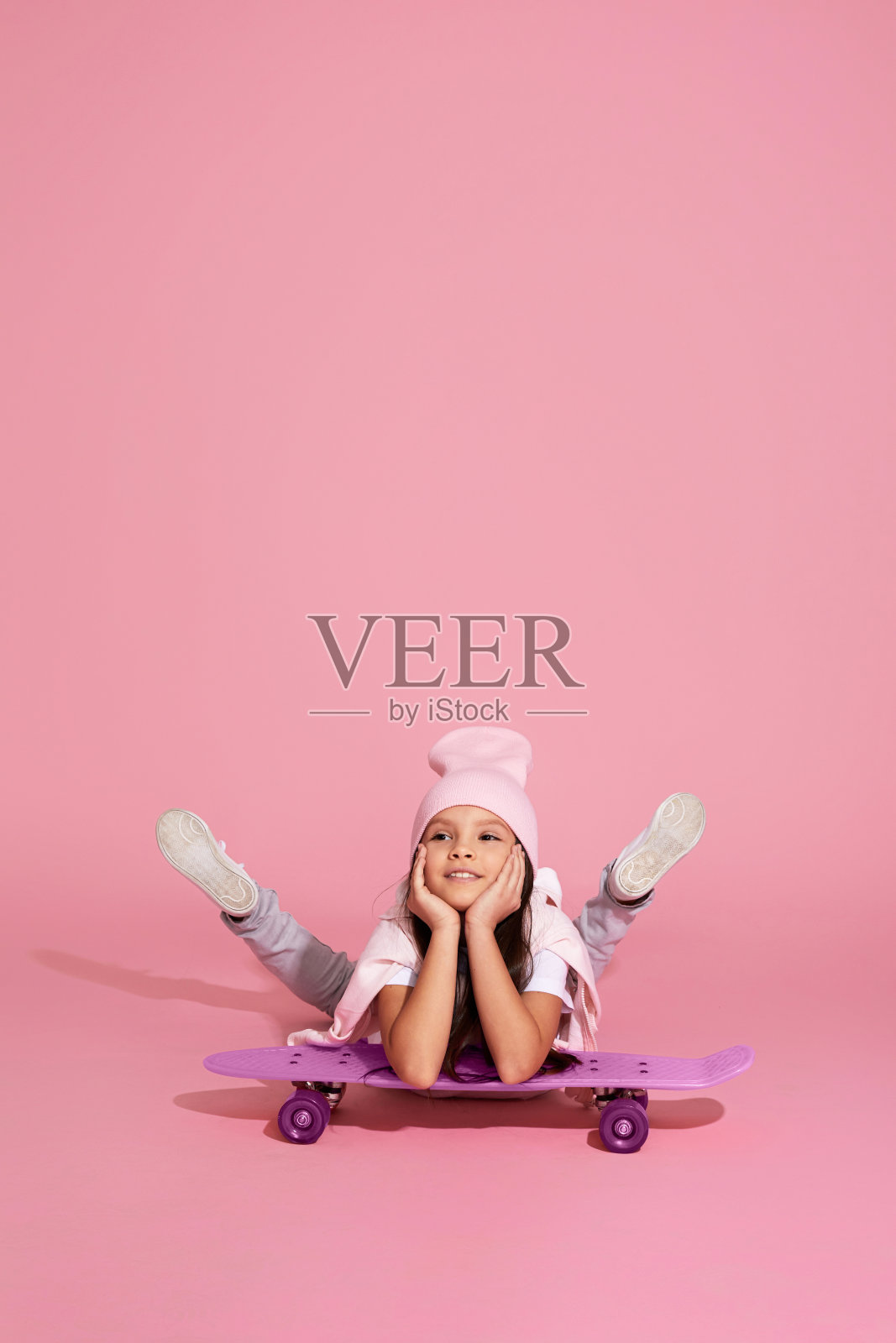 小女孩笑着坐在粉红色的滑板上照片摄影图片