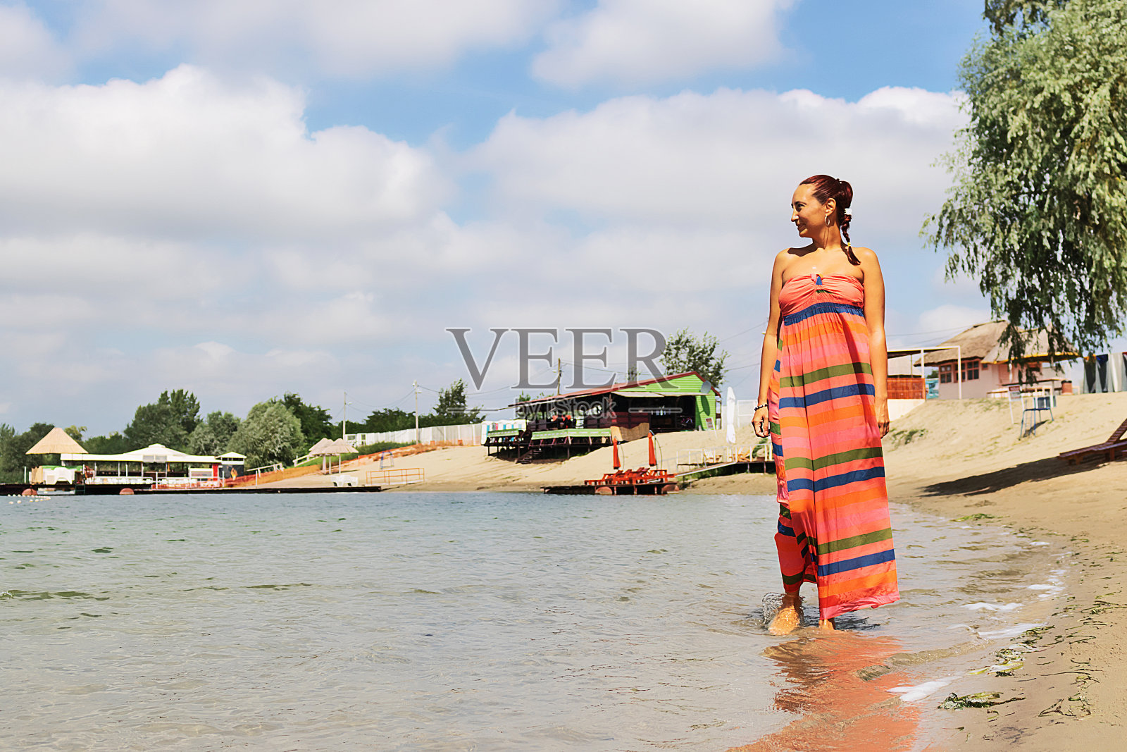 一个女人的全身在海滩上走过水。照片摄影图片