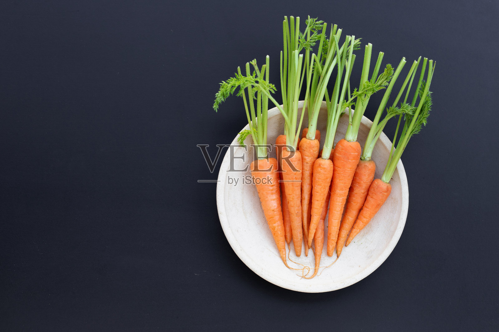 深色背景上的新鲜胡萝卜。照片摄影图片