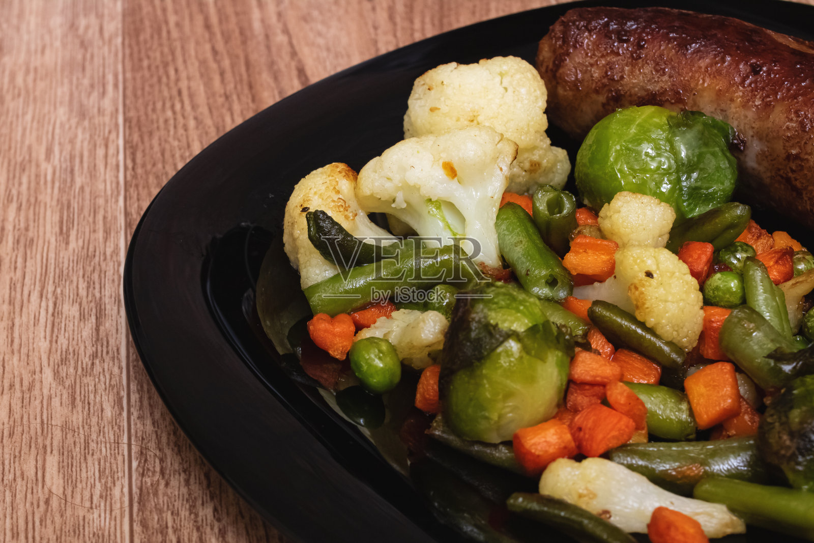 烤蔬菜和香肠放在黑色的盘子里照片摄影图片