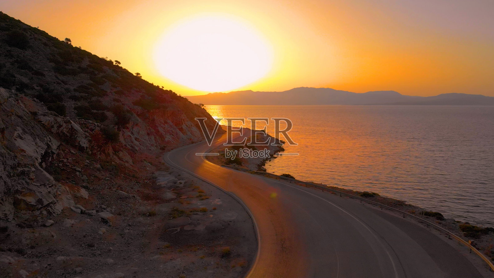 镜头光晕:夕阳照亮了风景如画的克罗地亚海岸公路照片摄影图片
