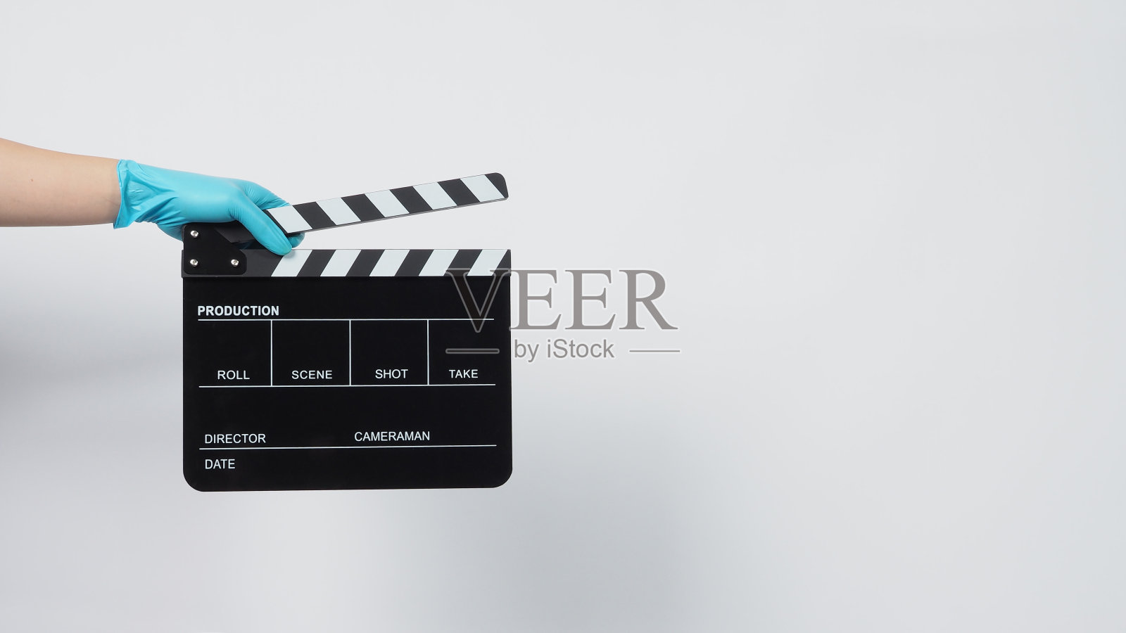 手戴手套，手持黑色拍板或电影板。它用于视频制作和电影工业上的白色背景。照片摄影图片
