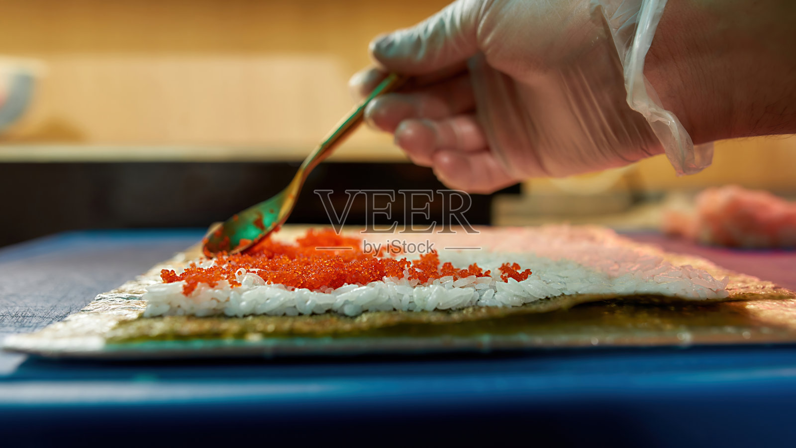 厨师将红鱼子酱涂在煮熟的米饭上，做成美味的卷饼照片摄影图片