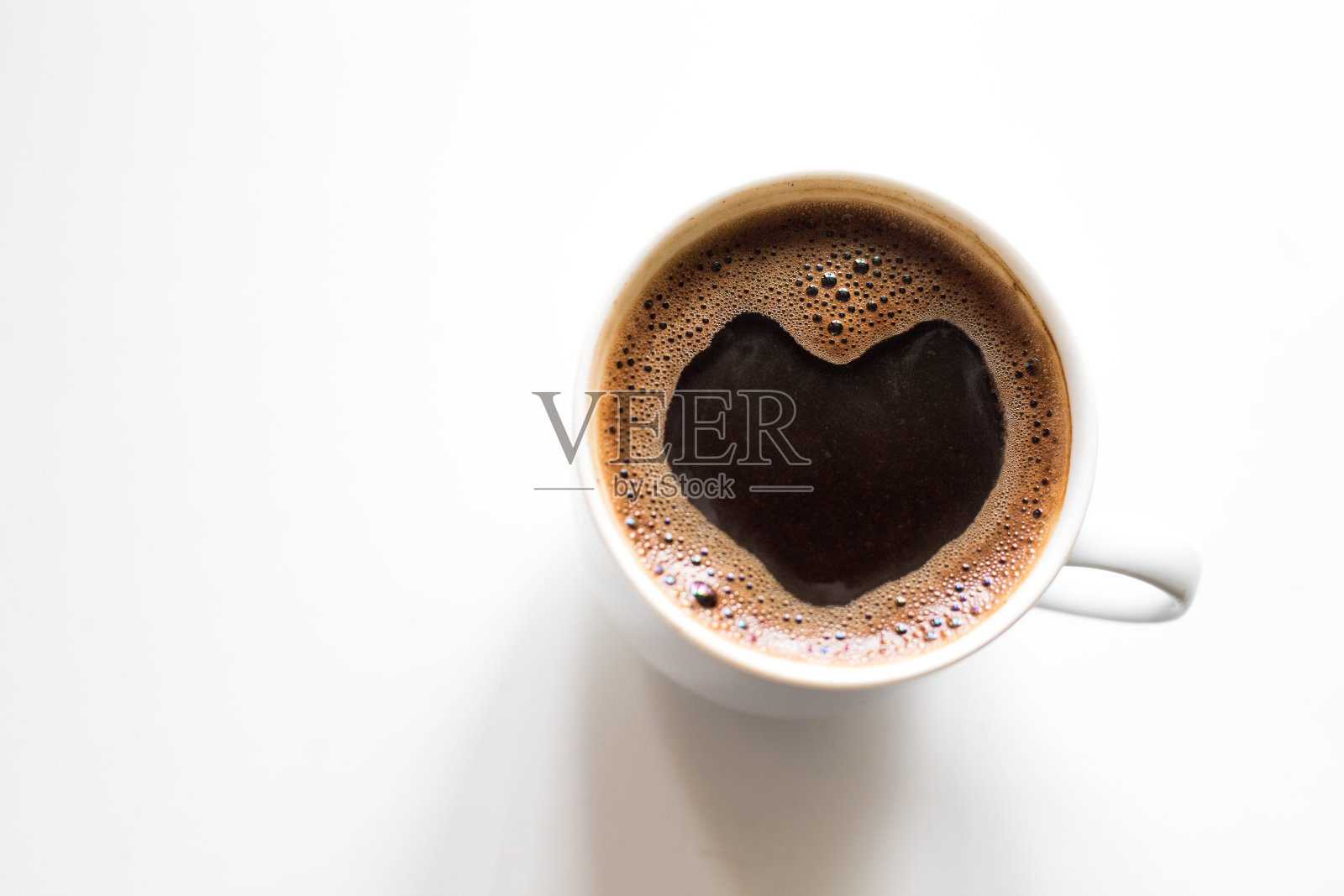 咖啡在杯子里，芳香的喝着，表面有一个心形的泡沫照片摄影图片