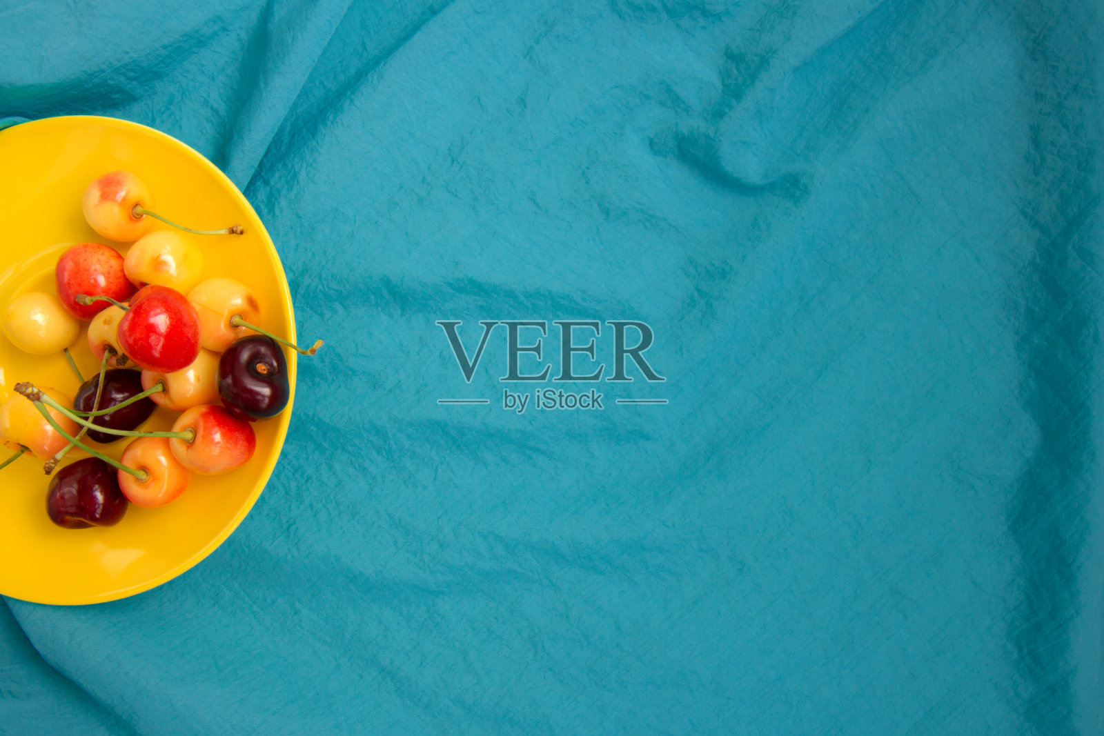 黄色盘子里的甜樱桃。新鲜水果。照片摄影图片