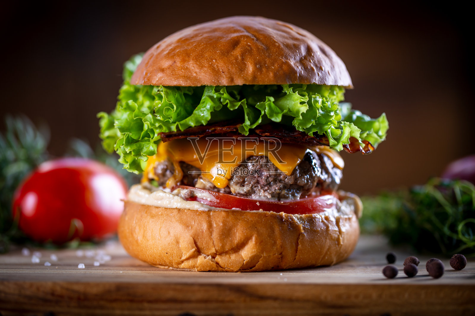 手工牛肉汉堡与切达干酪，培根，生菜和酱在木制的背景照片摄影图片
