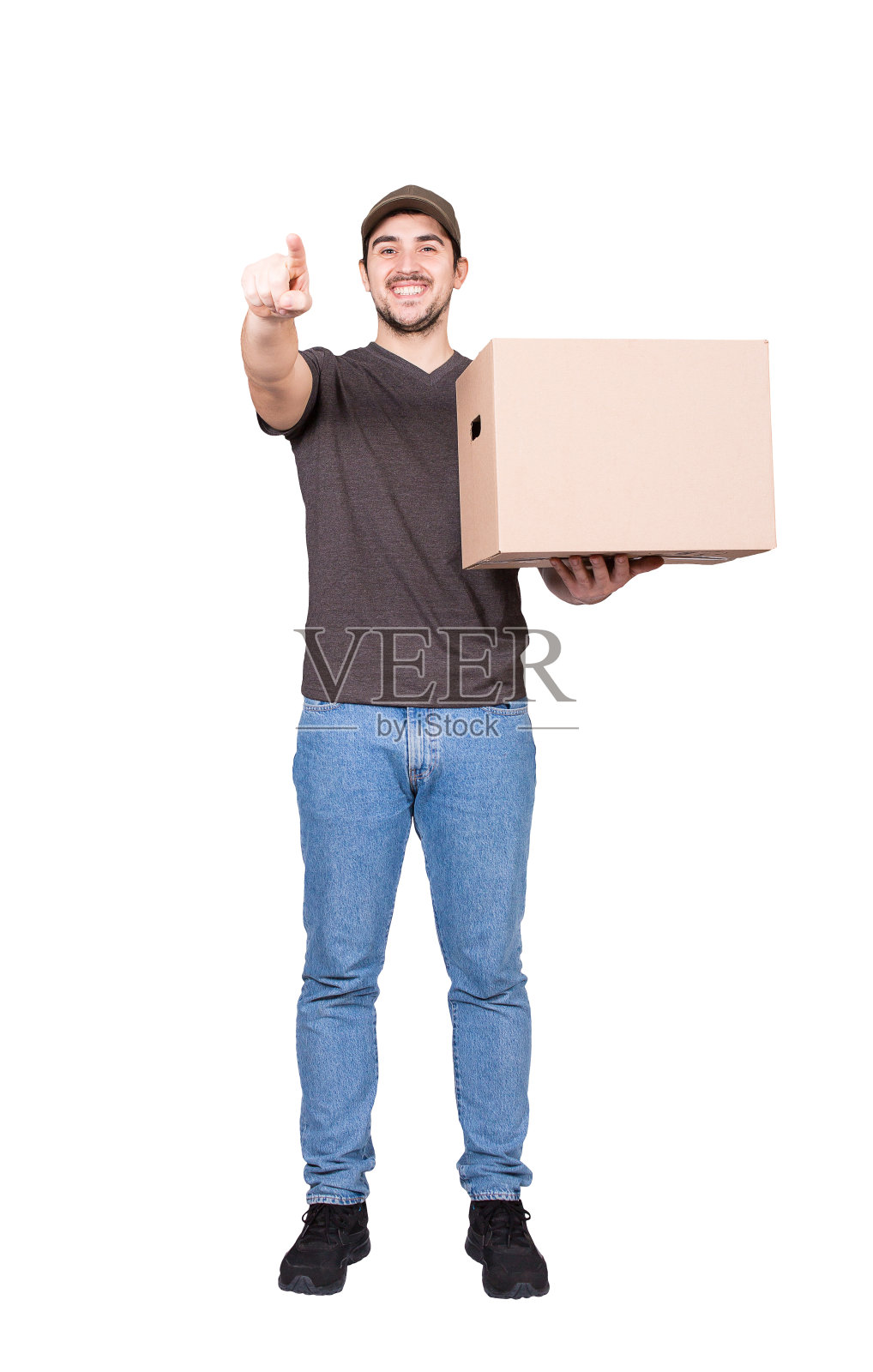 快乐的快递员，全身像，提着一个硬纸板包裹盒子指向他的食指对着相机，孤立在白色。快乐快递送包裹。卓越的客户服务理念照片摄影图片