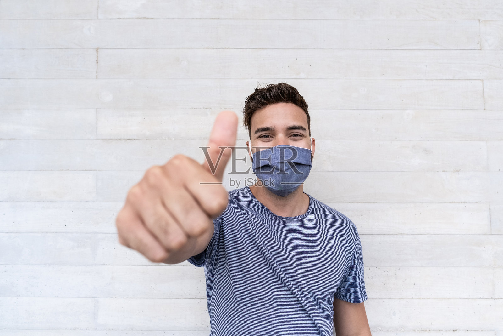 年轻的拉丁男子，拇指向上，戴着防护口罩应对冠状病毒爆发照片摄影图片