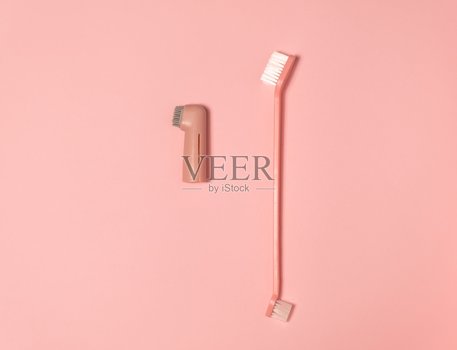 狗和猫用的牙刷。宠物牙齿护理包。兽医。粉色背景上有粉色和蓝色的牙刷。照片摄影图片