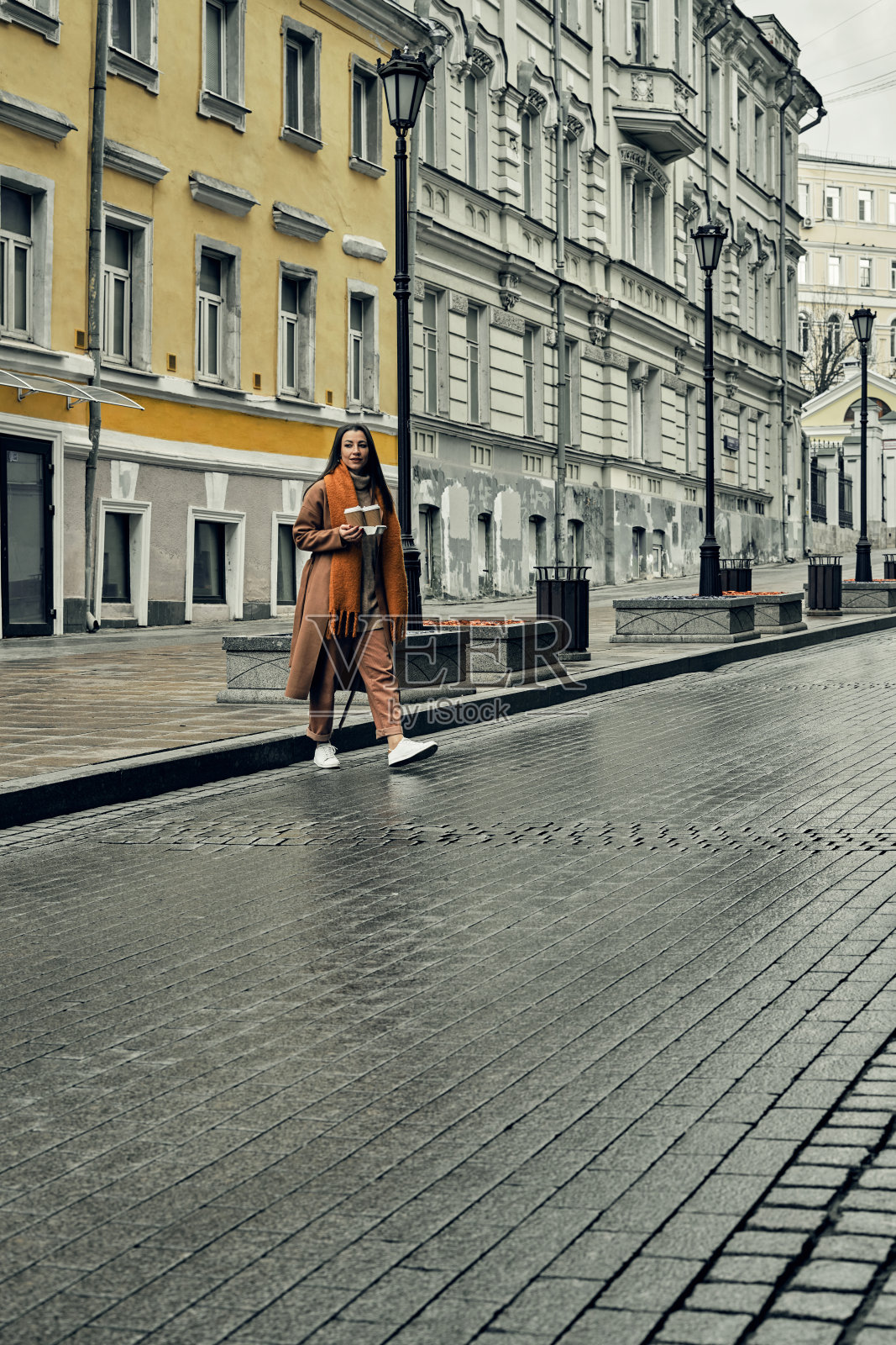 在街上拿着一次性纸杯的女孩。外卖，在城市里转转。照片摄影图片