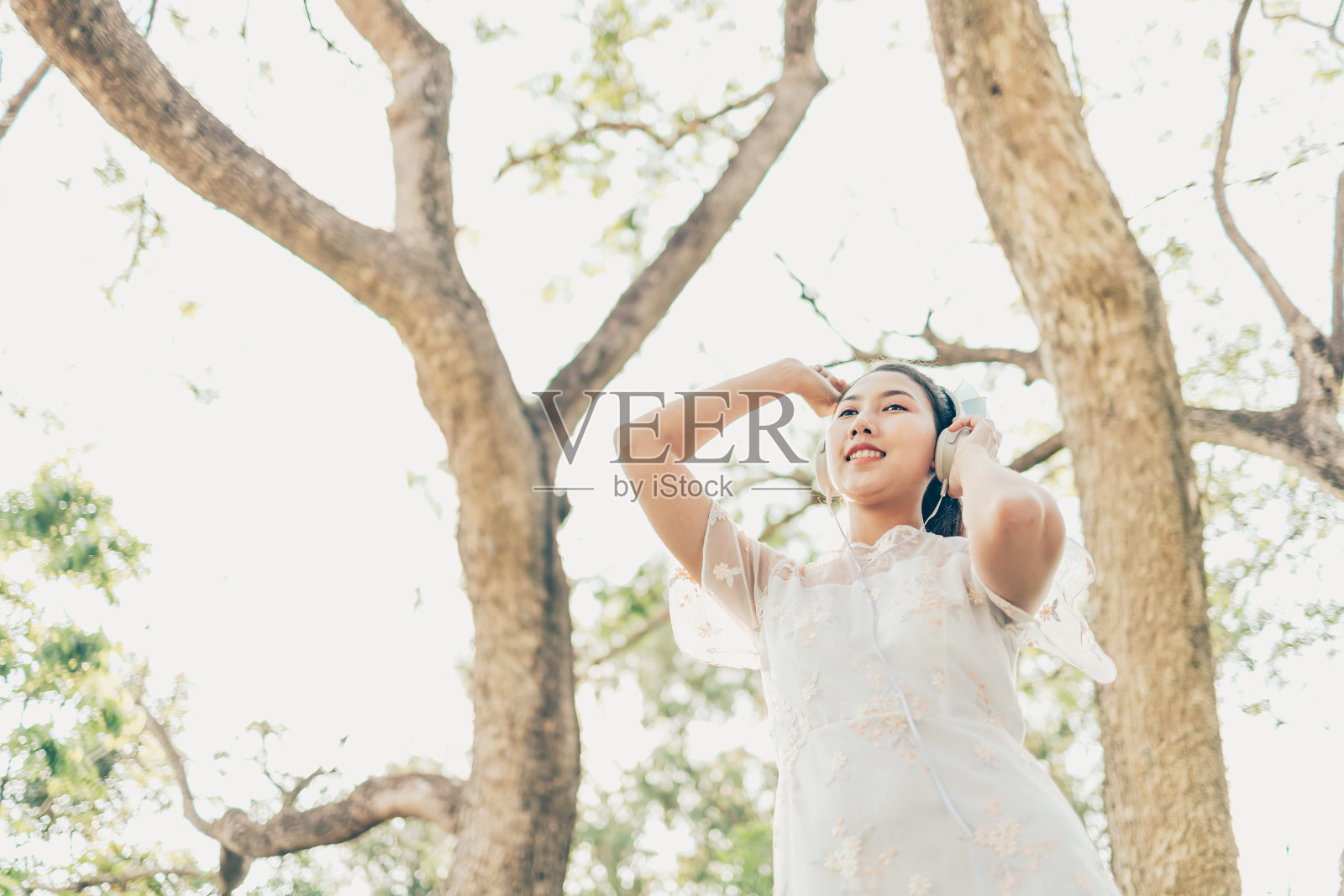 一个戴着耳机的女孩在森林里听音乐跳舞。音乐爱好和野餐概念。照片摄影图片