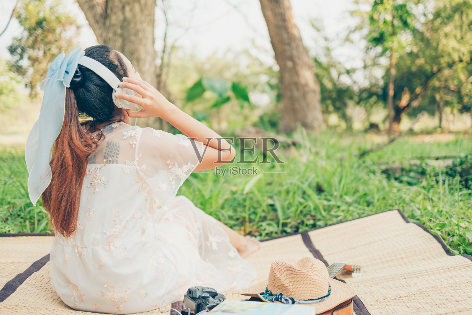 一个戴着耳机的女孩在森林里听着音乐跳舞。音乐爱好和野餐概念。照片摄影图片
