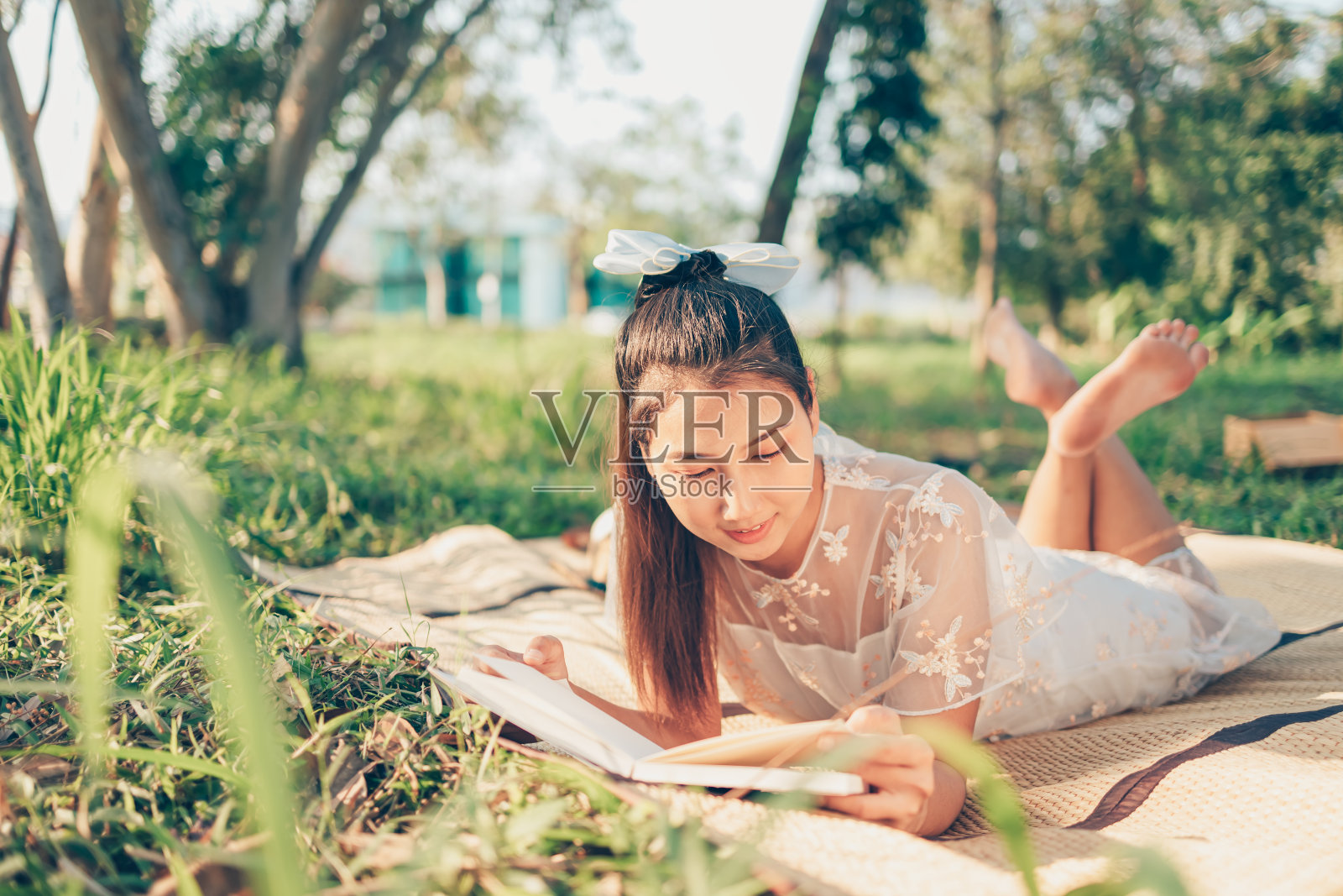 一个女孩在森林里的草席上看小说，森林里的夕阳。阅读爱好和野餐概念。照片摄影图片