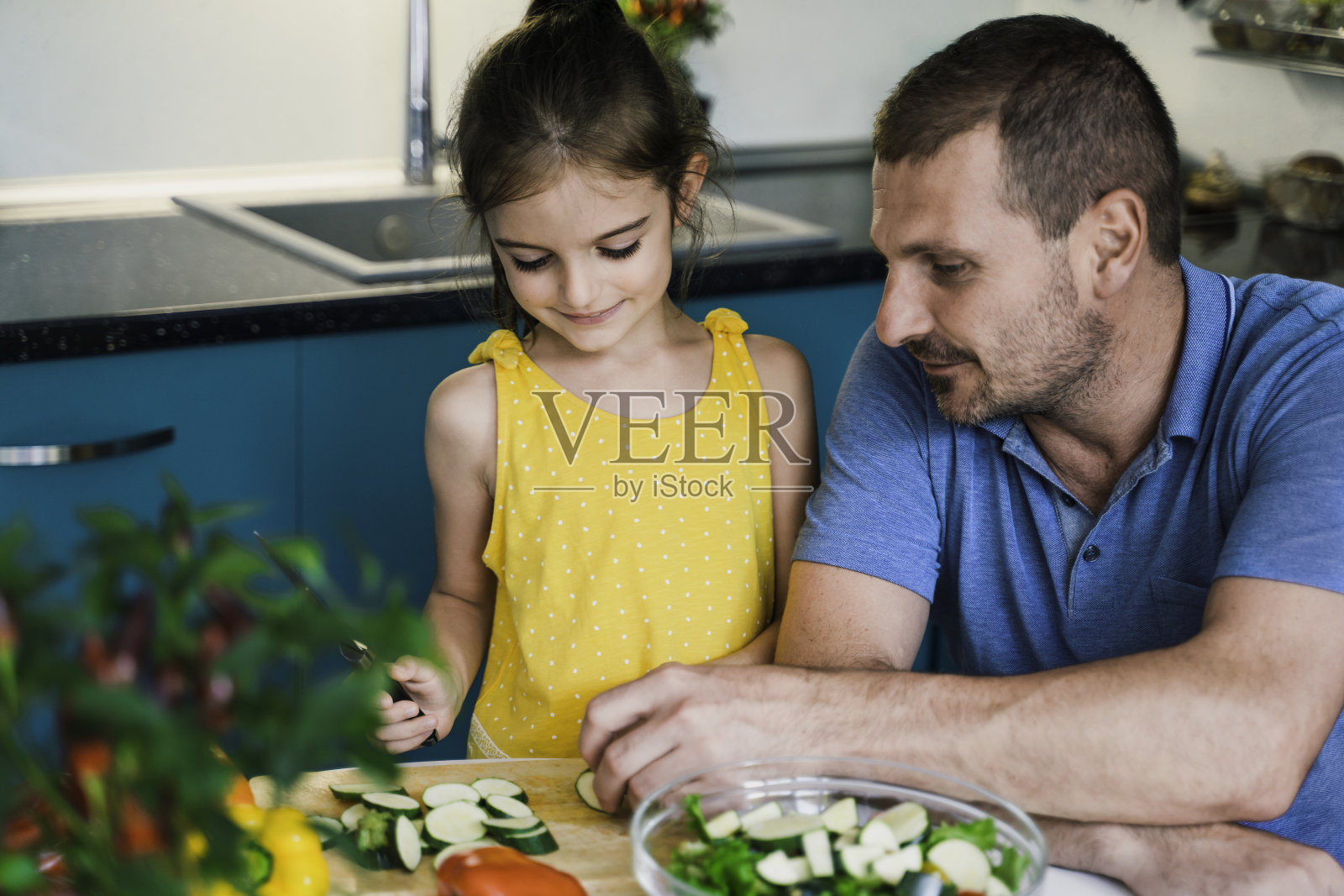 爸爸和他可爱的女儿在厨房里一起做沙拉照片摄影图片
