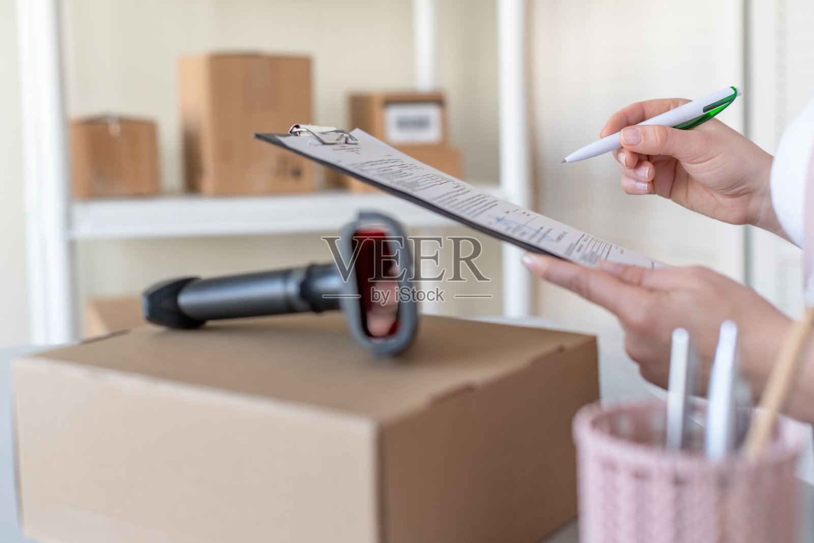 邮局女职员用条码扫描仪扫描包裹确认发送客户。送货上门服务。照片摄影图片