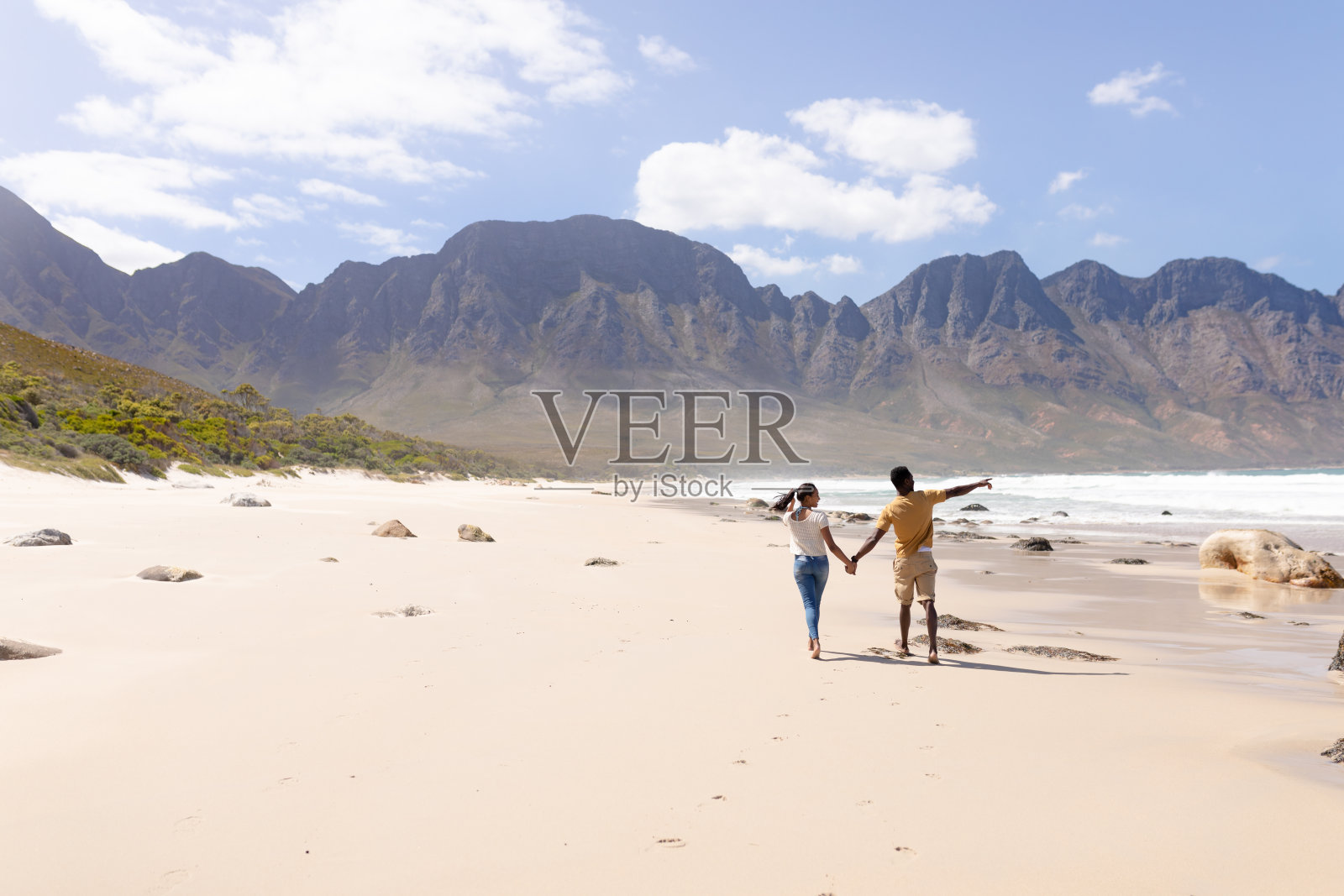 一对非裔美国夫妇手牵着手在海边的沙滩上散步照片摄影图片