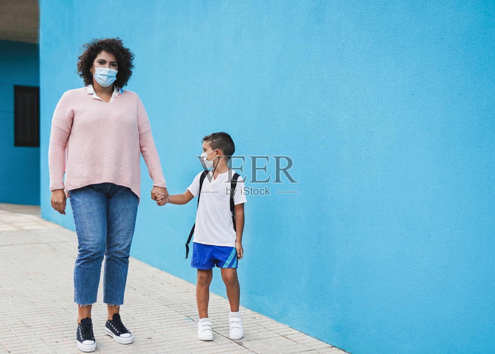 母亲带着口罩牵着孩子走路-学校安全措施的概念-母子之爱照片摄影图片