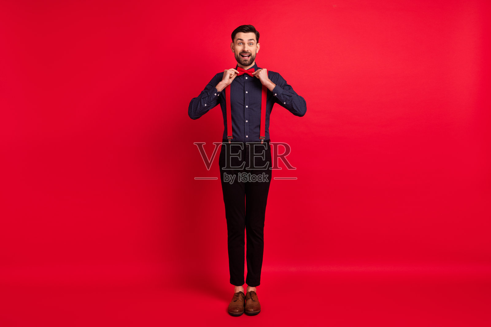 全尺寸照片的年轻快乐兴奋开朗英俊的绅士调整蝴蝶结孤立在红色背景照片摄影图片