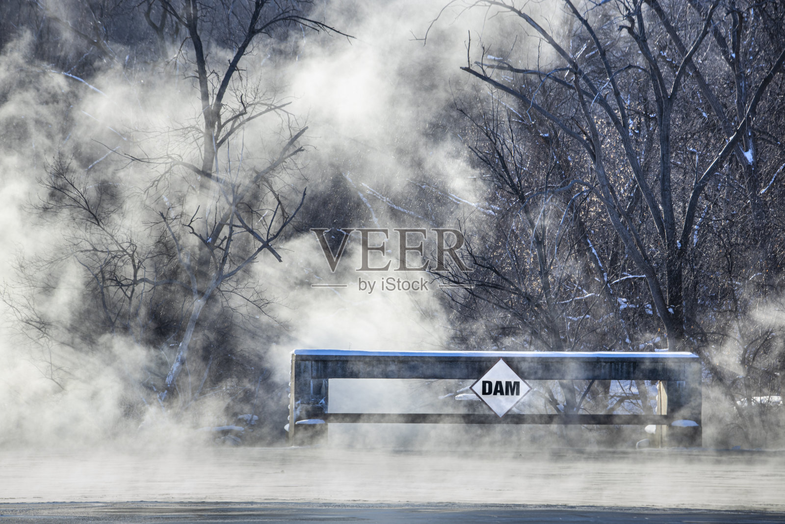 在极端寒冷的天气下，水在大坝旁冒着蒸汽。大坝冷照片摄影图片