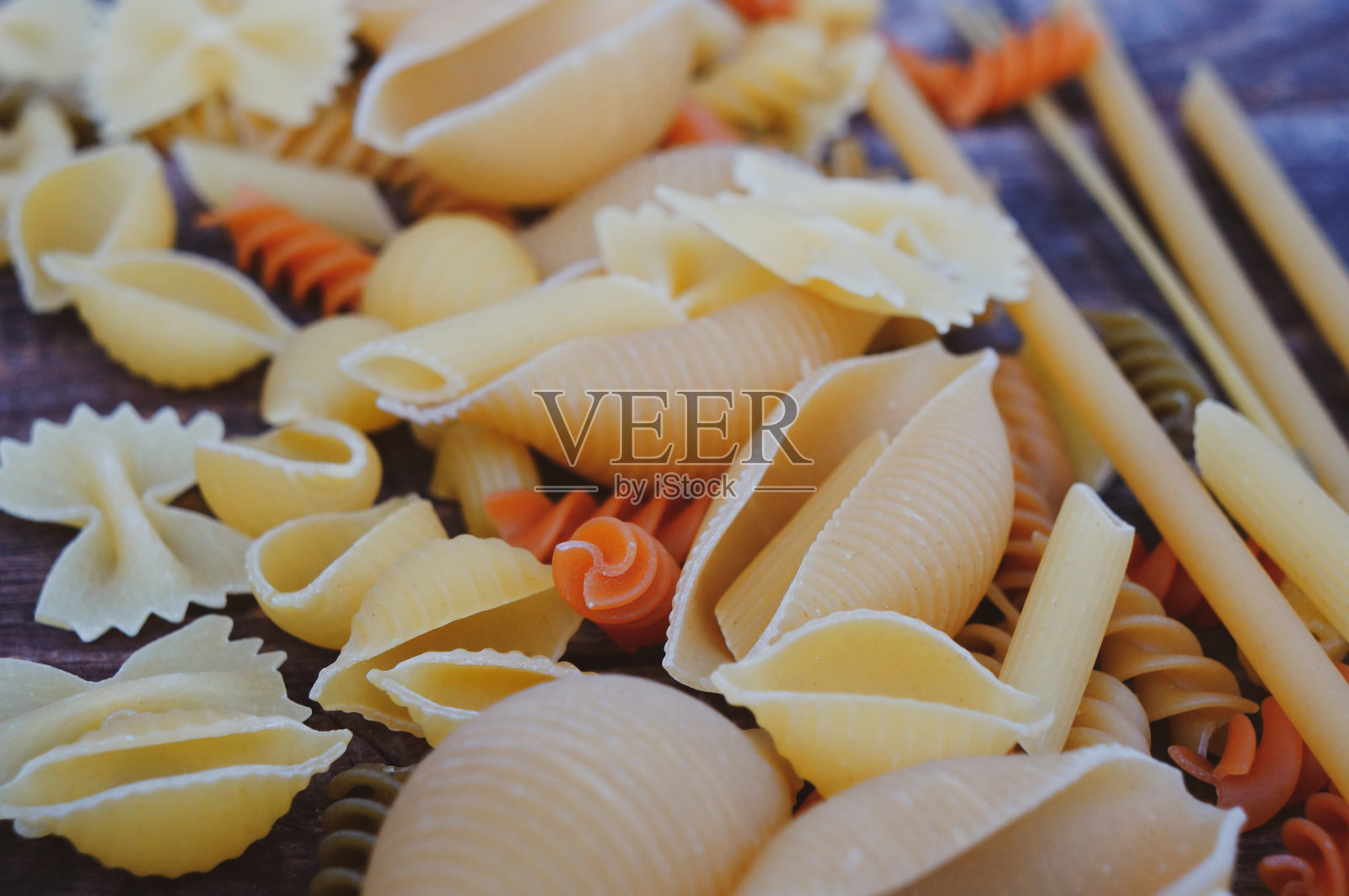 深色木桌上放着干意面。照片摄影图片