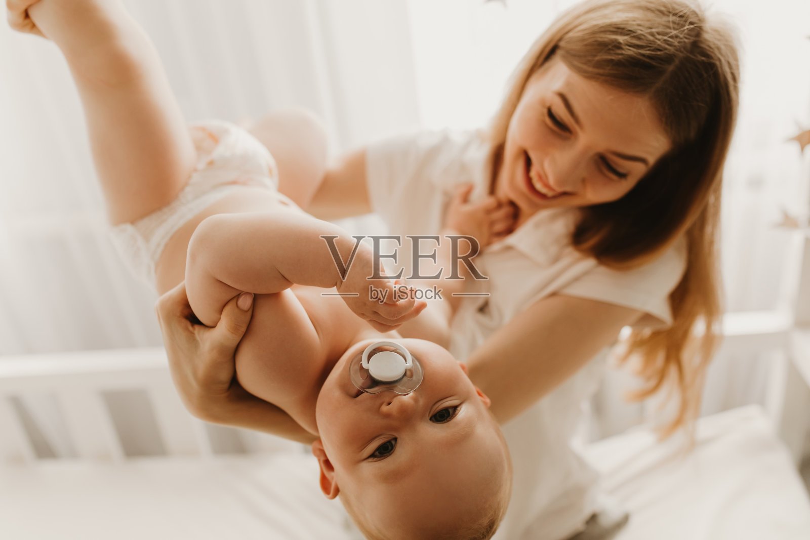 一个快乐的家庭，年轻的妈妈在玩耍，把她的宝宝举到空中照片摄影图片