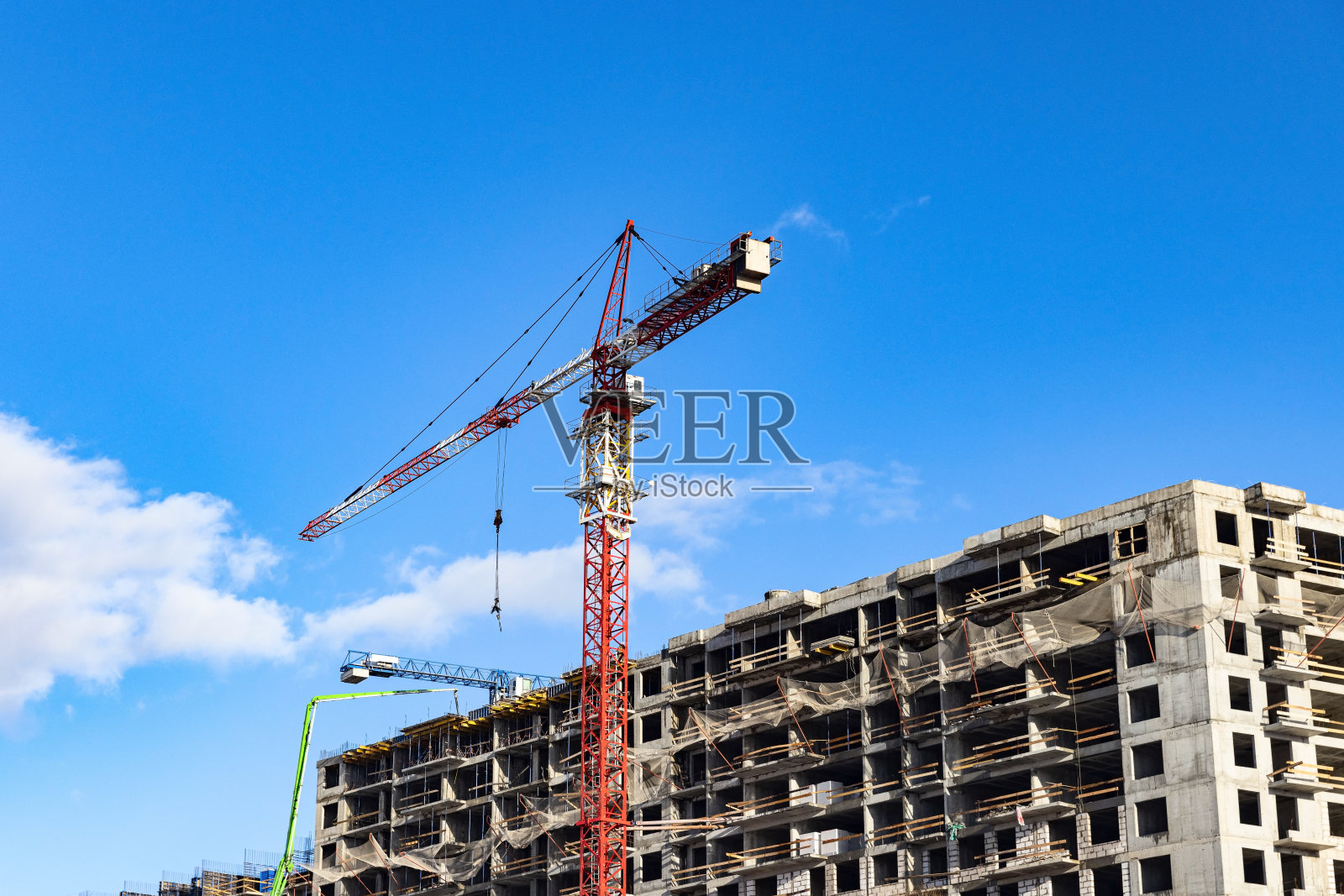 施工塔吊在楼房(公寓)的工地上，对着蓝天照片摄影图片