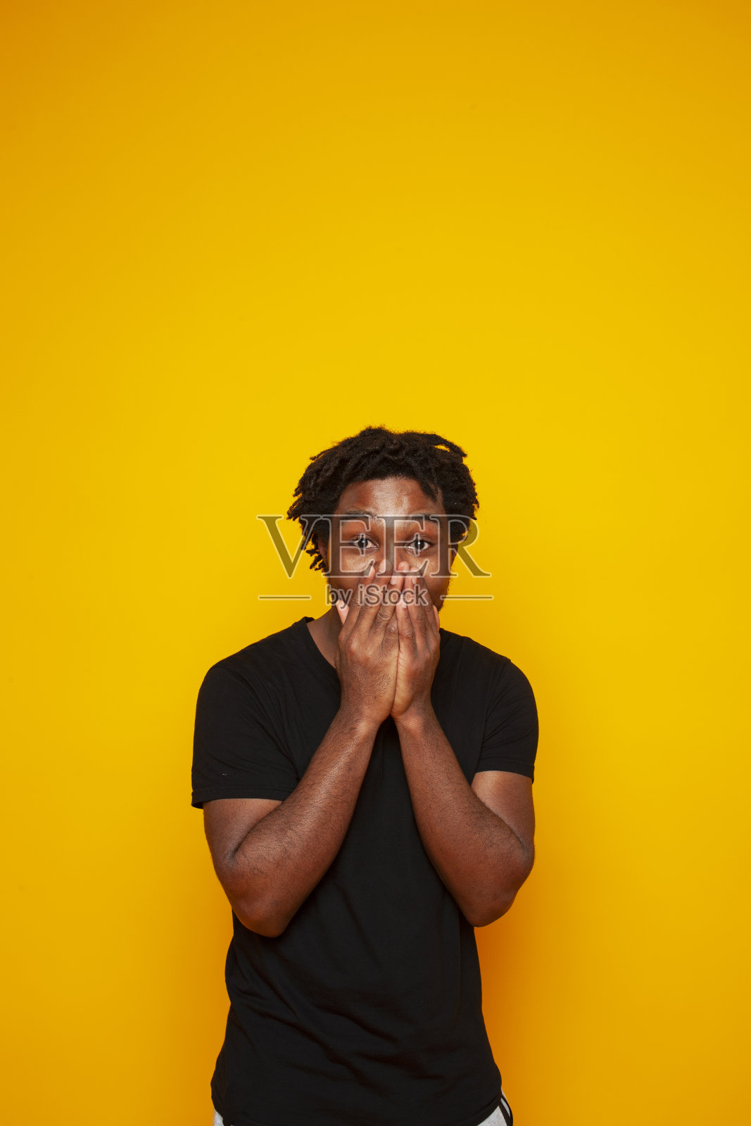 年轻英俊的非裔美国男生摆出开朗的姿态，在黄色的背景下，生活方式人的概念照片摄影图片