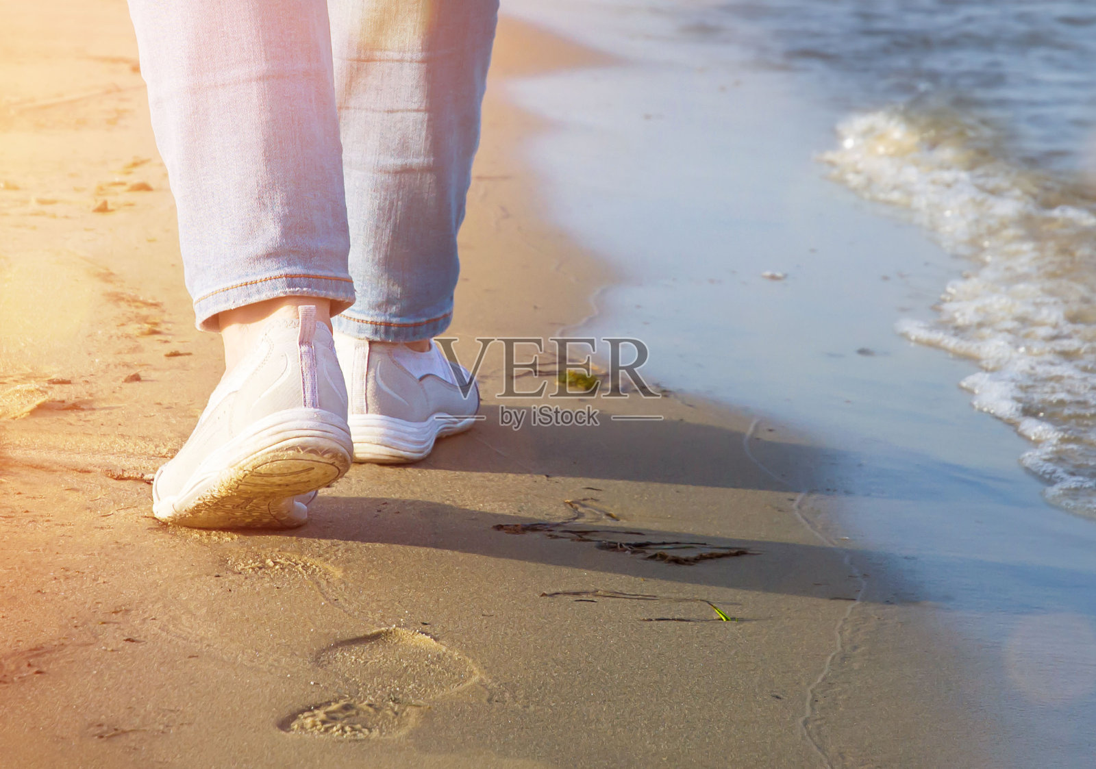一个女孩的腿沿着河岸走的特写照片摄影图片