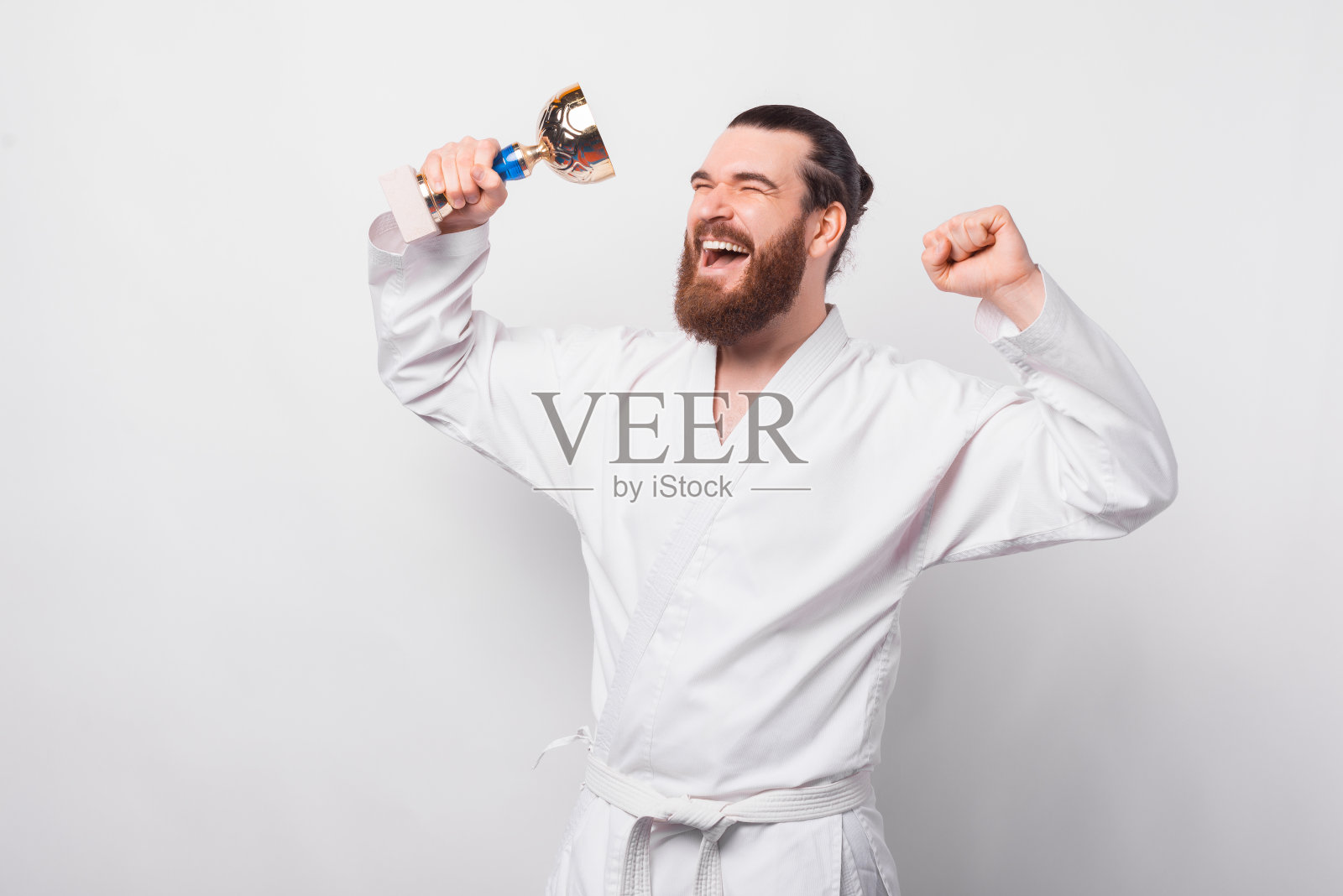 惊奇的大胡子拳手跆拳道男子持有金杯和庆祝照片摄影图片
