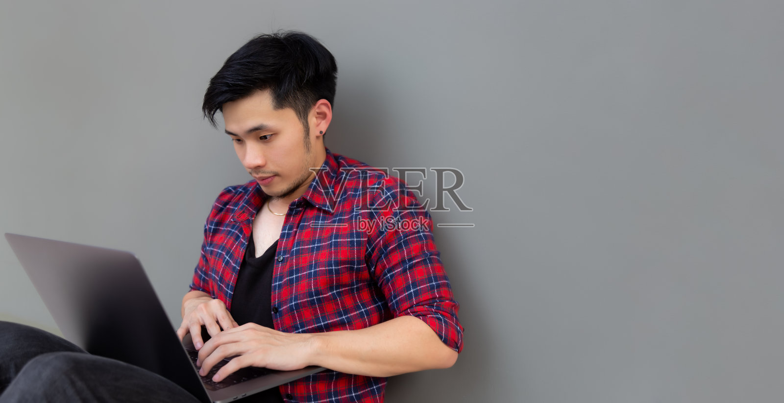 年轻英俊的自由职业者坐在地板上，空闲时间与新的现代笔记本电脑大学生用笔记本电脑在线学习照片摄影图片