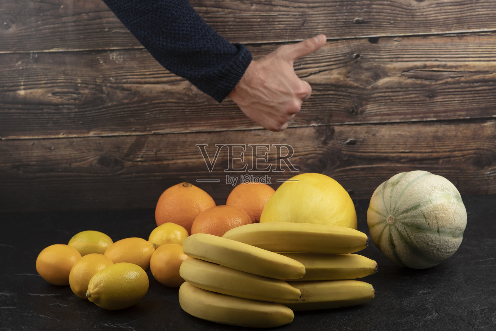 在黑色的桌子上，男性的手对着新鲜的水果竖起大拇指照片摄影图片