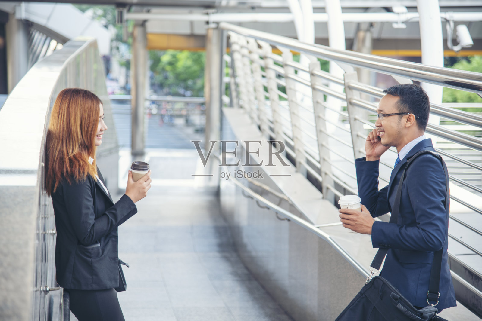 在城市里用智能手机喝咖啡。手牵手带走咖啡杯和智能手机一起聊着生意伙伴喝着咖啡照片摄影图片