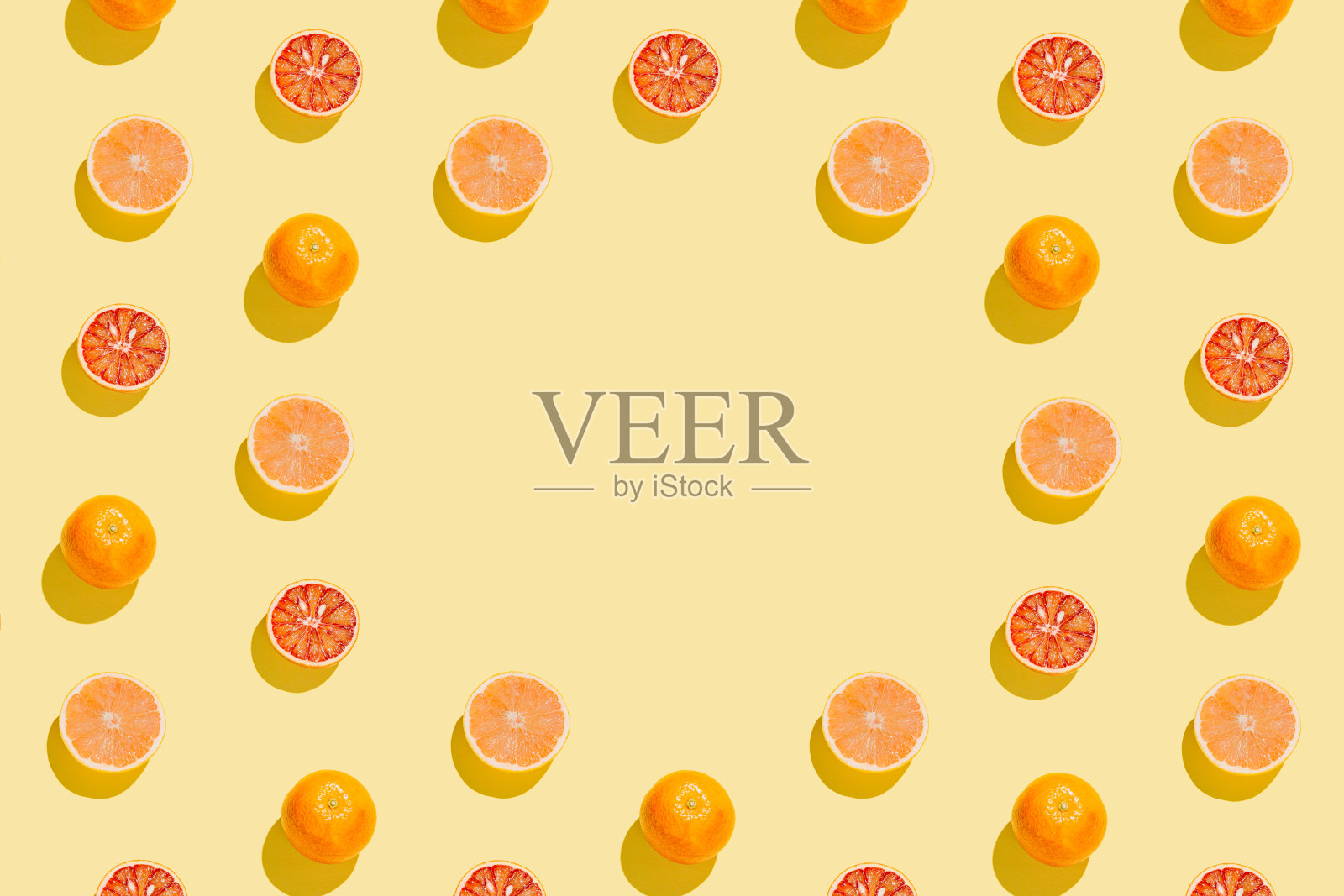 用切好的葡萄柚和血橙在黄色的背景上做成的创意图案。夏季水果的概念。阳光公寓。俯视图照片摄影图片