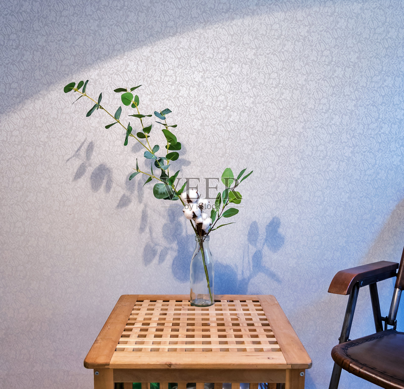 一个玻璃瓶，上面有桉树枝和棉花，放在一张木桌上照片摄影图片