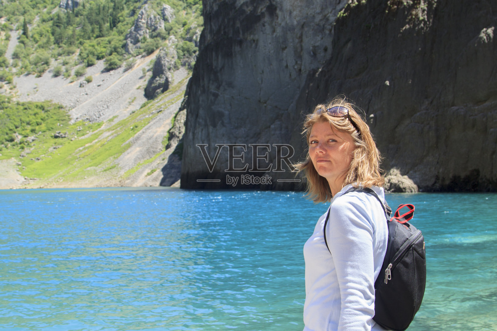 背后背着黑色背包的女孩望着山间蓝色的喀斯特湖照片摄影图片