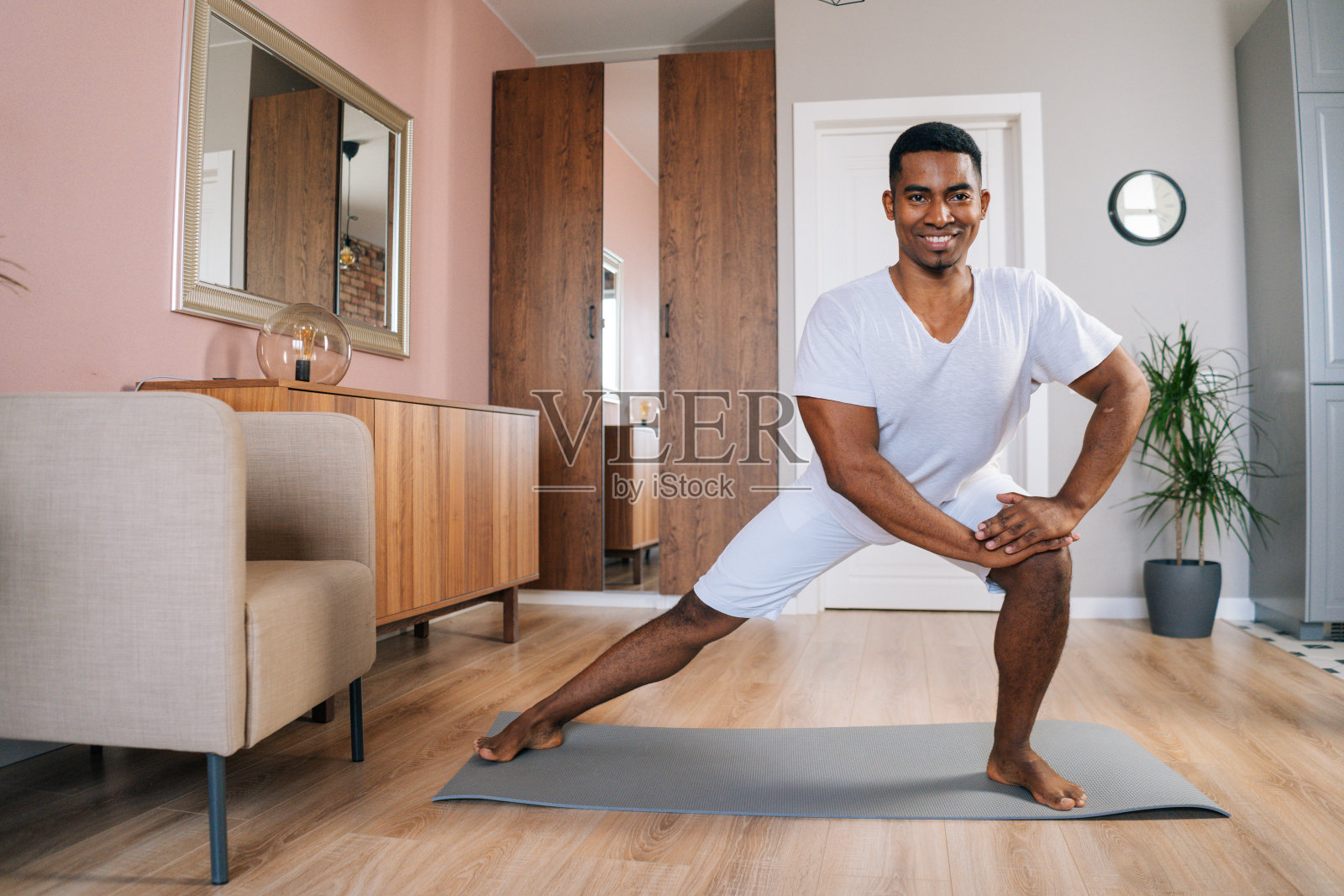 正面视图微笑强壮的非洲裔美国人在家里做侧弓步运动照片摄影图片