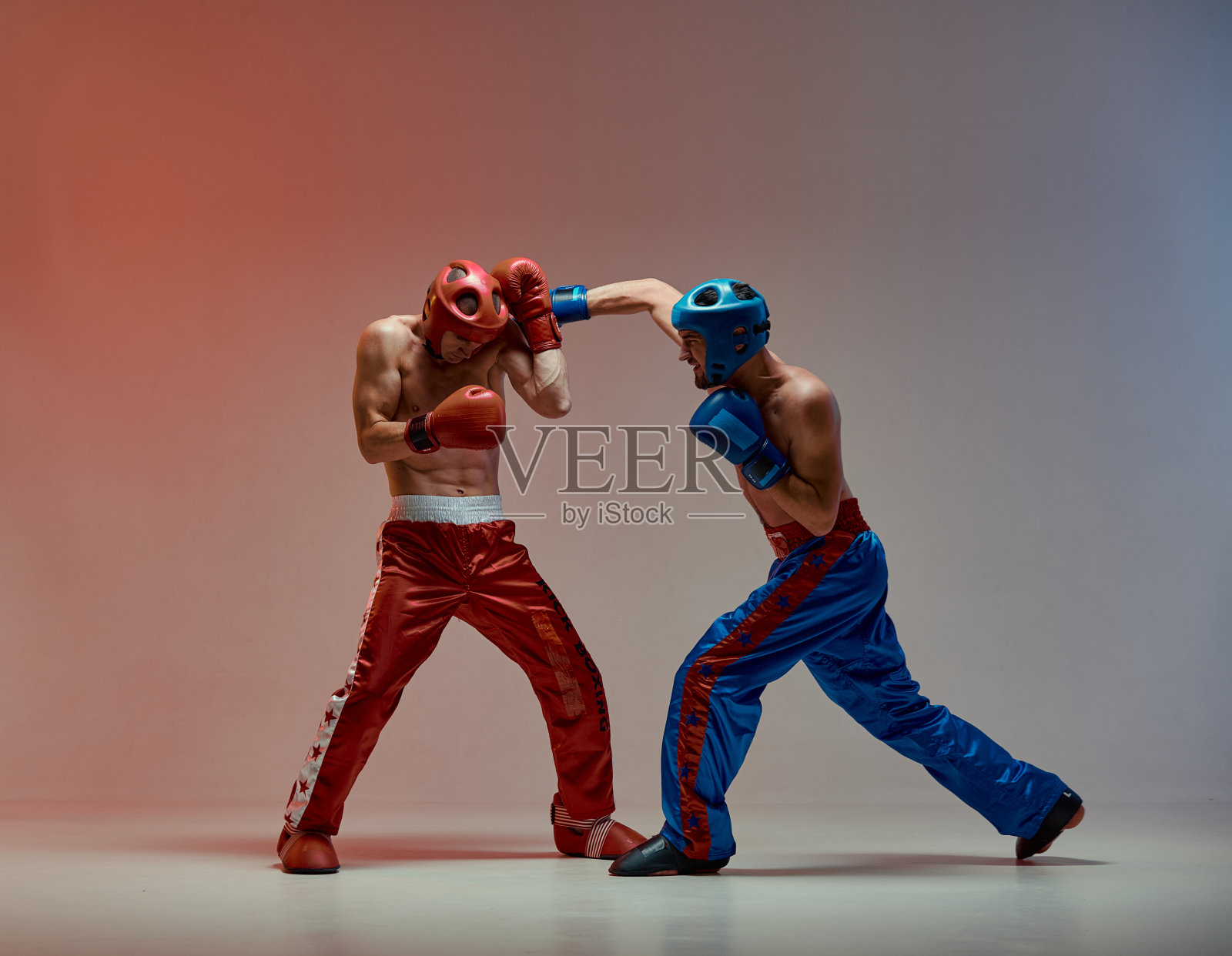 格斗男子在拳击手套和头盔在战斗中在红色演播室光，武术照片摄影图片