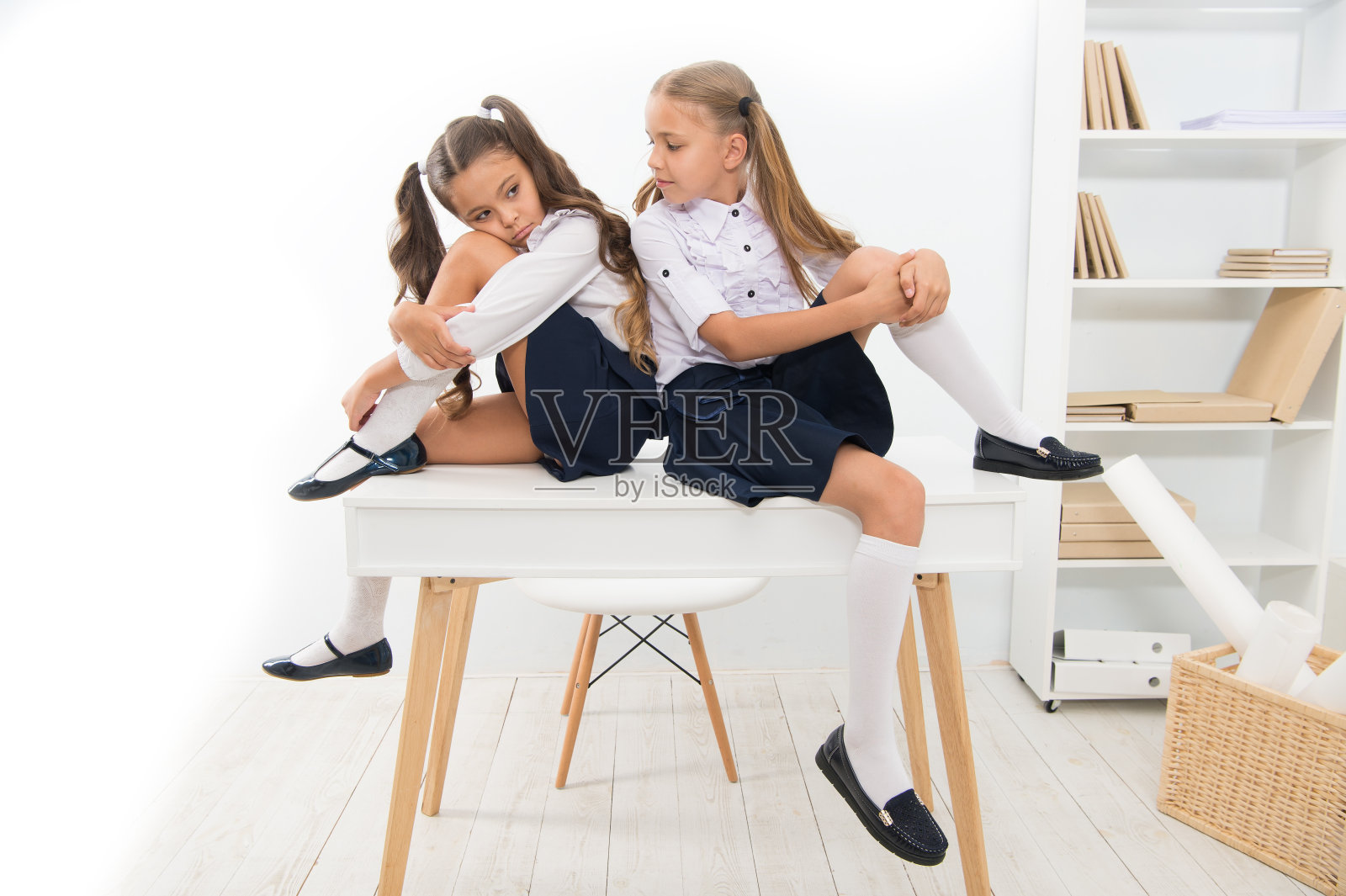 一个无聊的课。可爱的孩子们坐在餐桌旁。小女孩们在小学厌倦了上课。小女孩在学校上课时感到无聊。史上最无聊的课照片摄影图片