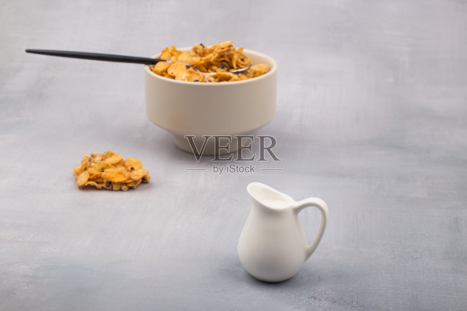 一碗玉米片、麦片和一勺孤立在灰色背景上。照片摄影图片