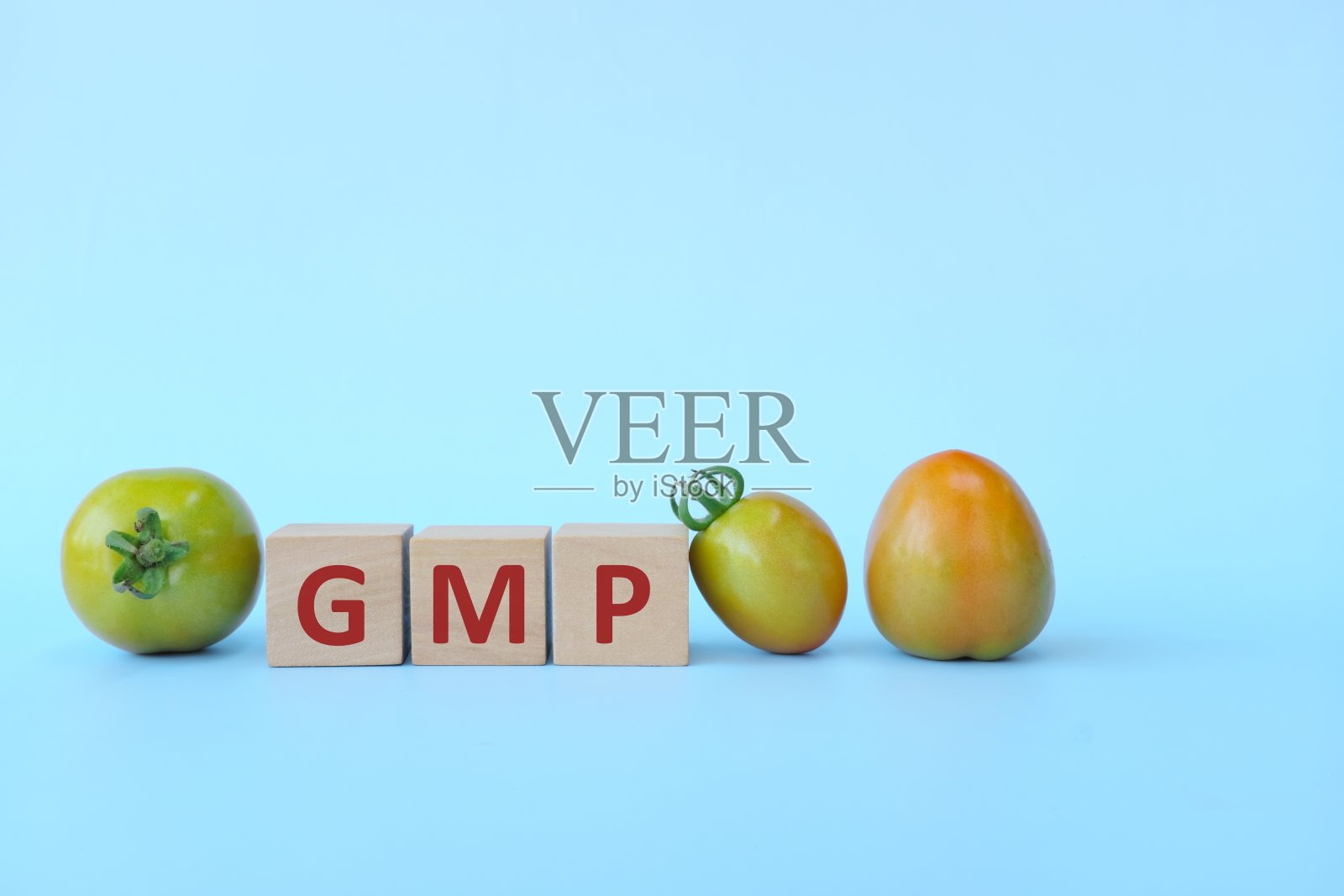 GMP字文本在蓝色背景的木块复制空间和番茄水果。食品工业良好生产规范。照片摄影图片