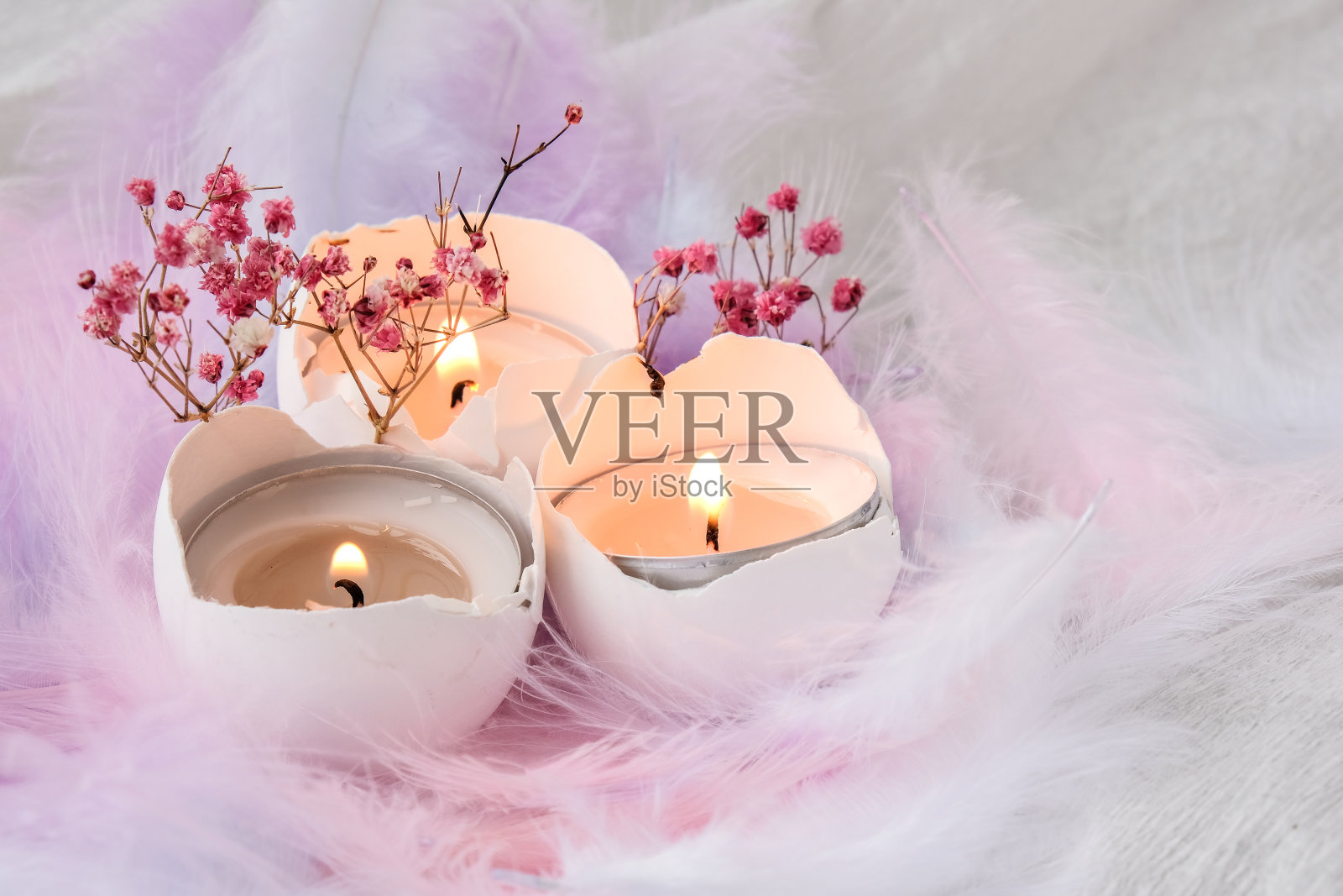 由白色蛋壳组成，里面有蜡烛。烛光。用鸟羽毛装饰的明亮的复活节装饰。柔和的颜色。复活节贺卡照片摄影图片