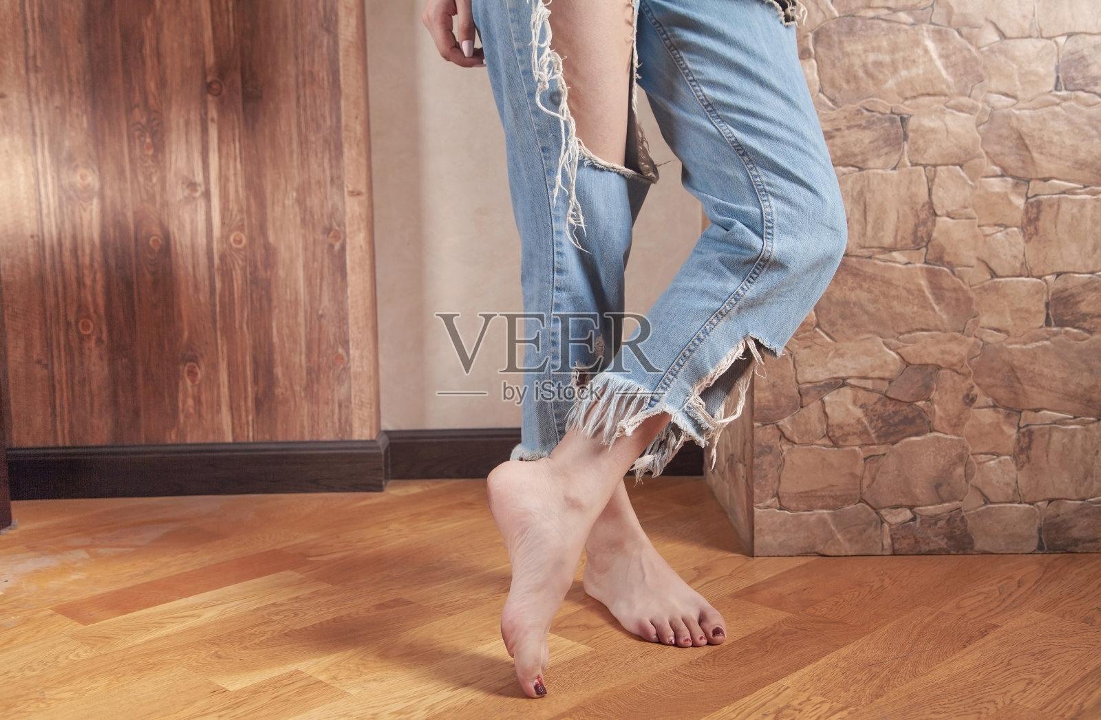 年轻女子穿着现代破牛仔裤在家。照片摄影图片