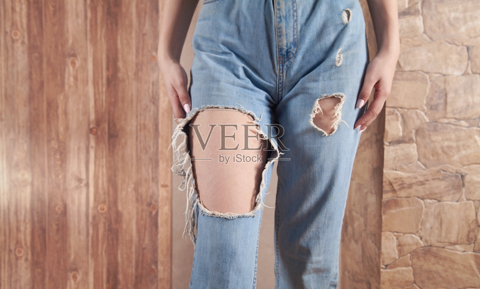 年轻女子穿着现代破牛仔裤在家。照片摄影图片