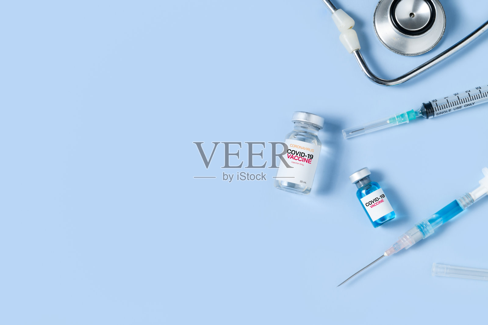 装有注射器和听诊器的小瓶Covid - 19疫苗，蓝色背景，照片摄影图片