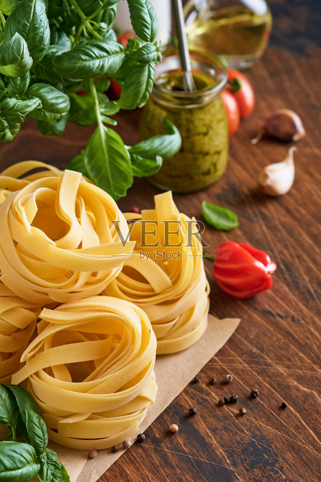 自制的意式扁面在棕色的纸上，在白色的背景上加上橄榄油，酱汁，罗勒和大蒜。照片摄影图片